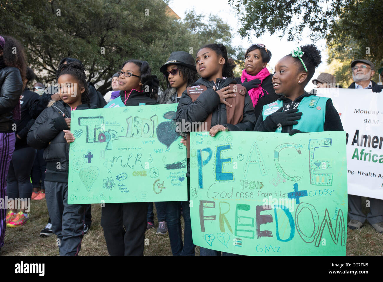 Black Girl Scouts hold signs paying tribute to Martin Luther King's messages of peace and freedom at MLK Day march in Austin TX Stock Photo