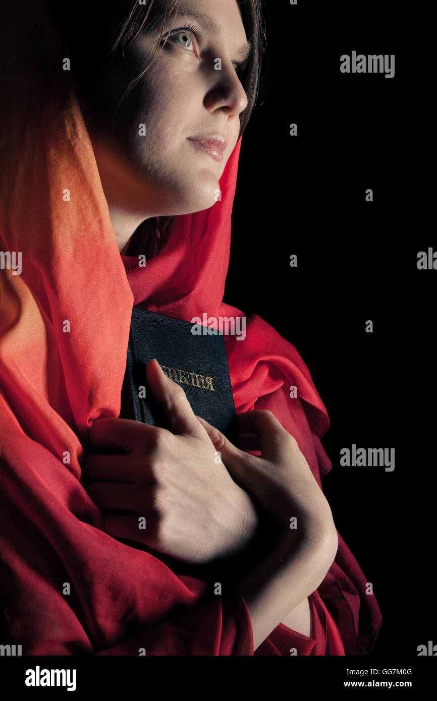 Woman with a Bible in the night. Isolated on a black background Stock Photo
