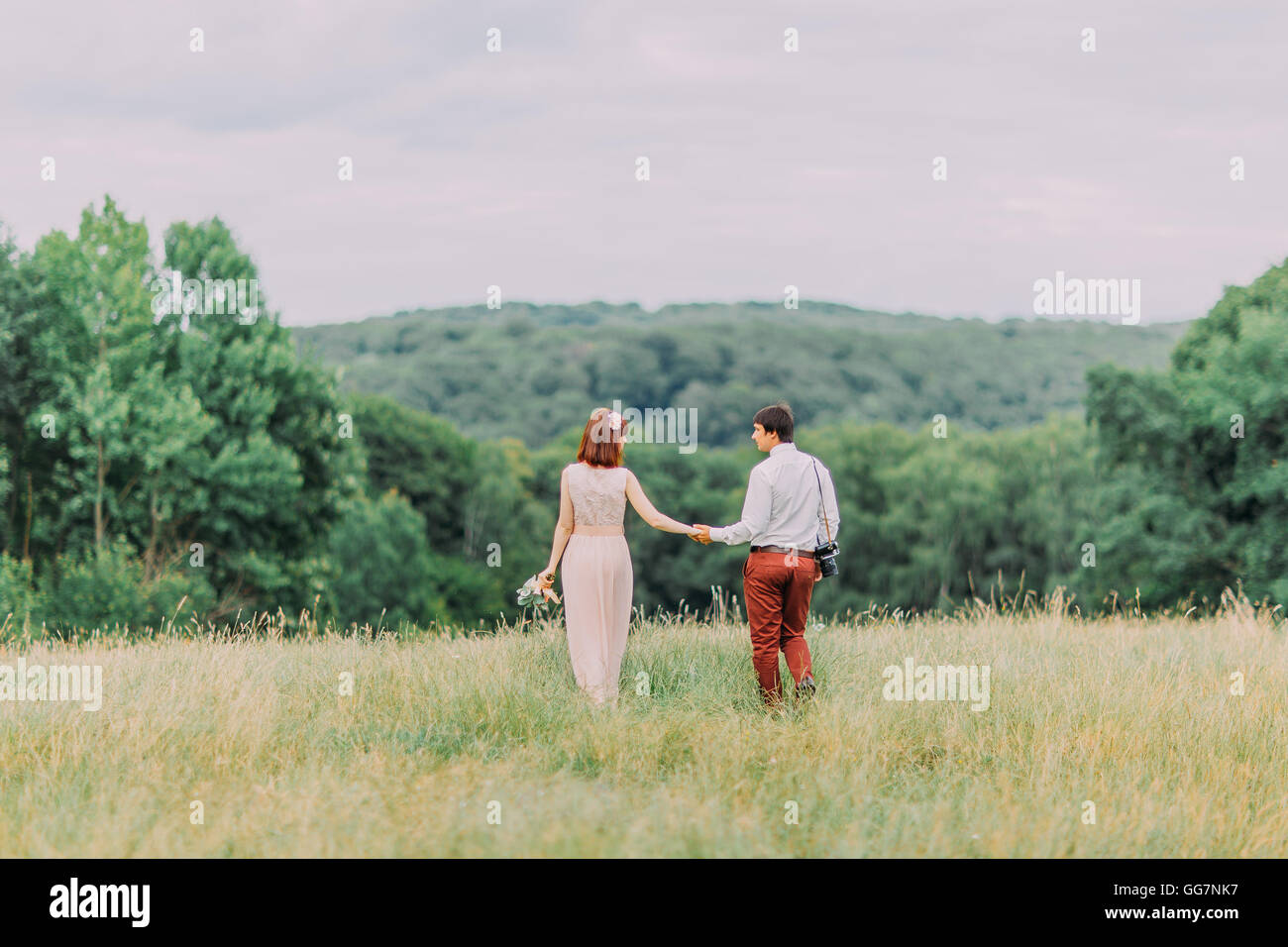 Gorgeous wedding and beautiful couple of young people walking holding ...