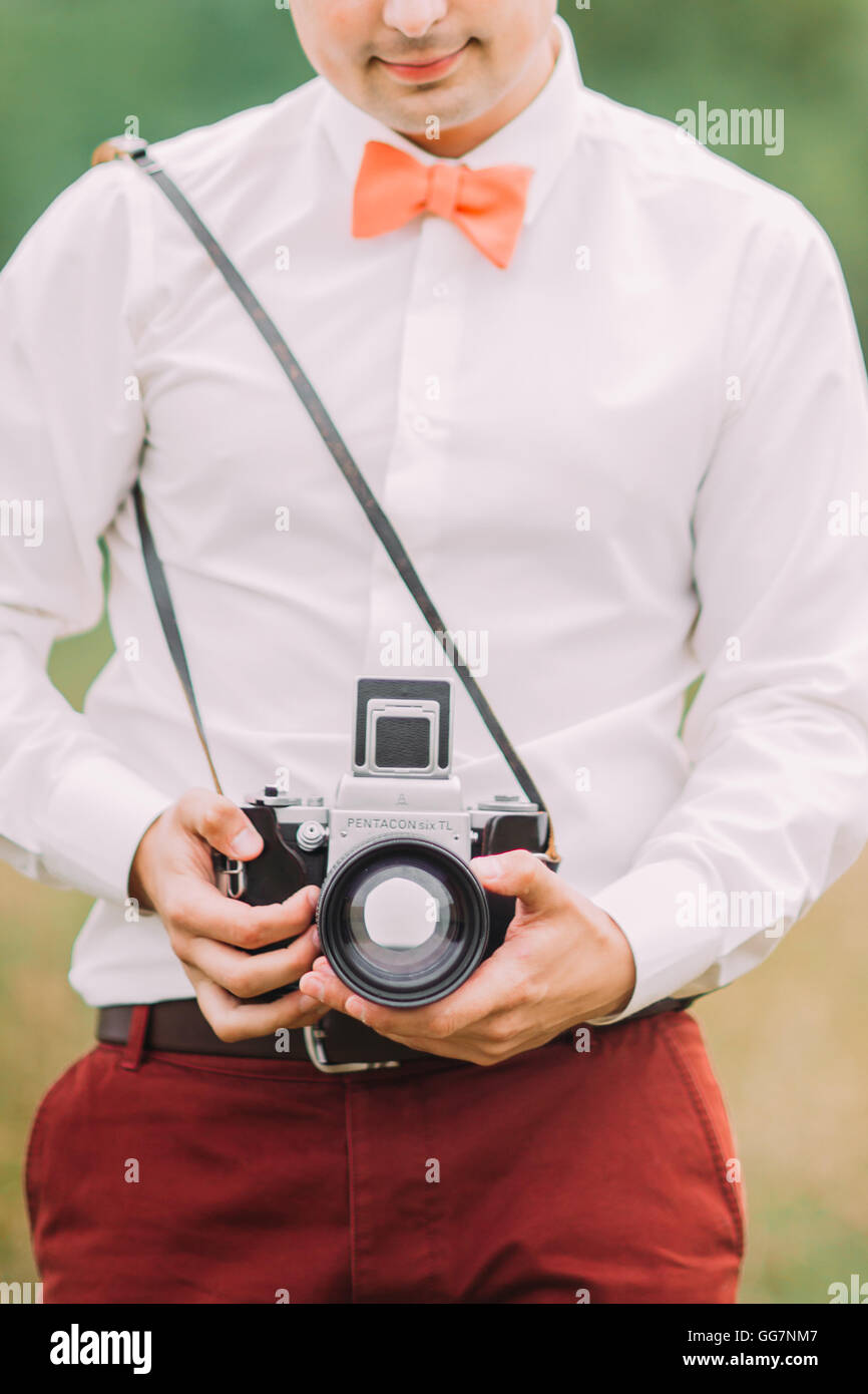 Man adjusts a retro film camera before snapshot, close shot of hands and photocamera Stock Photo