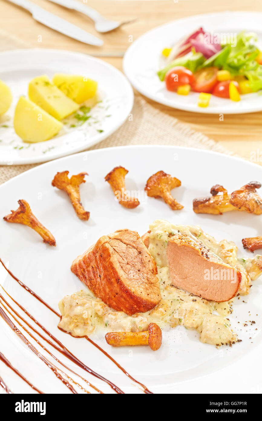 Roasted pork loin and chanterelles with creamy chanterelle sauce and vegetables. Stock Photo
