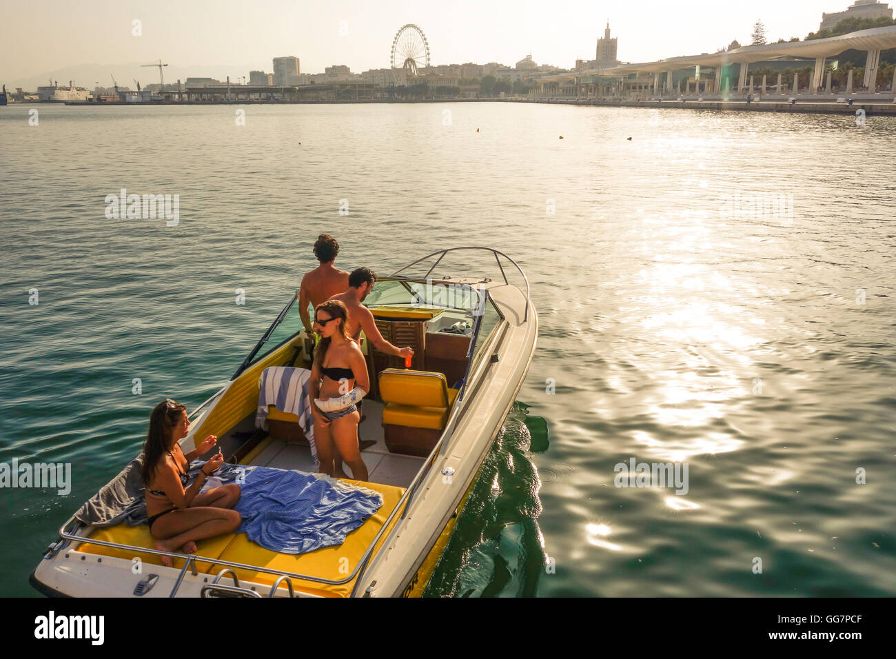 Two young couples in motor boat leaving port of Malaga, Spain. Stock Photo