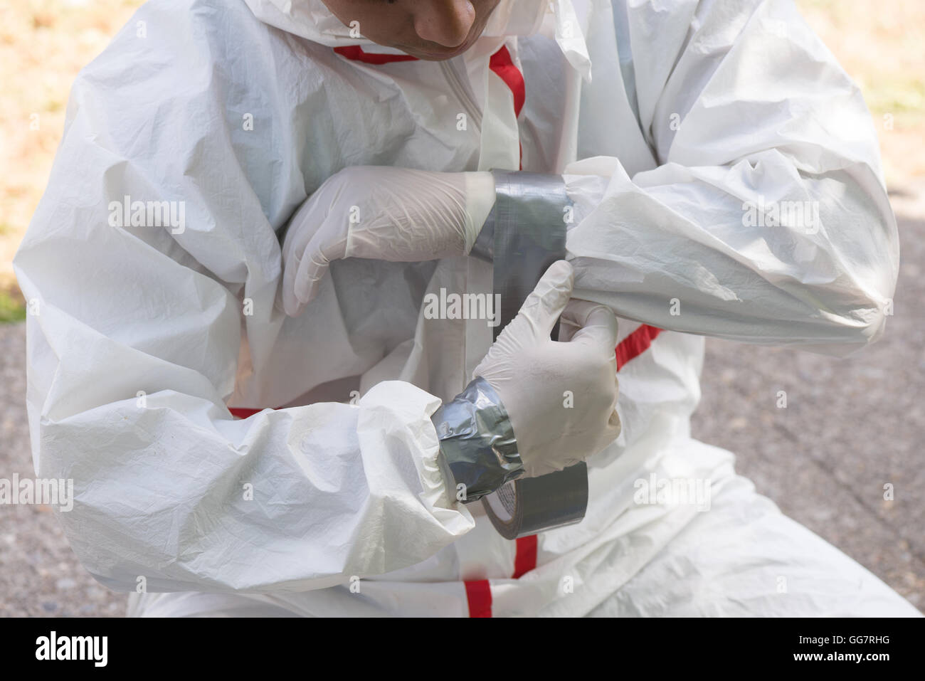 A house painter secures the sleeves of his hazmat suit preparing to safely remove lead paint. Stock Photo