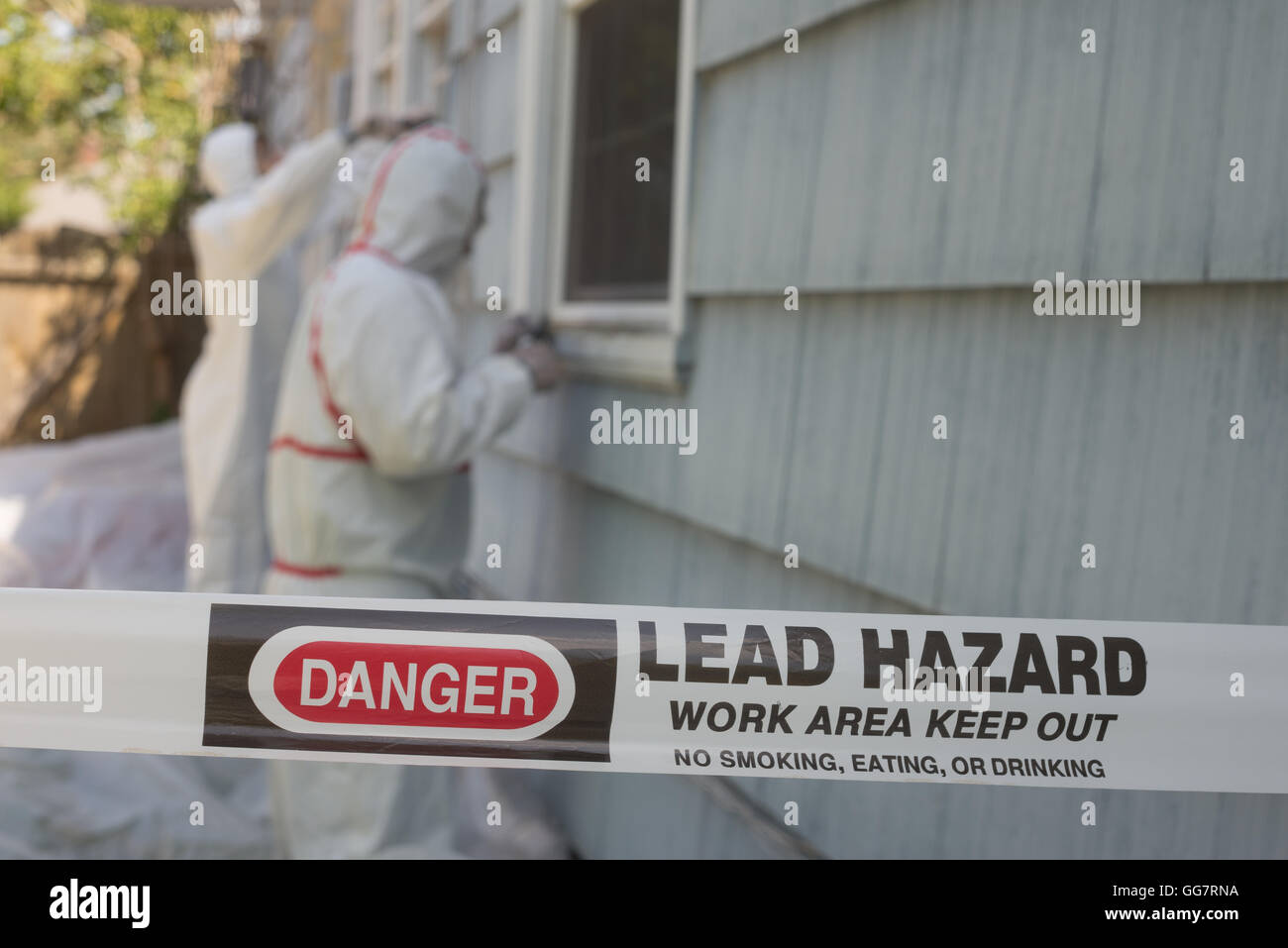 Two house painters in hazmat suits removing lead paint from an old