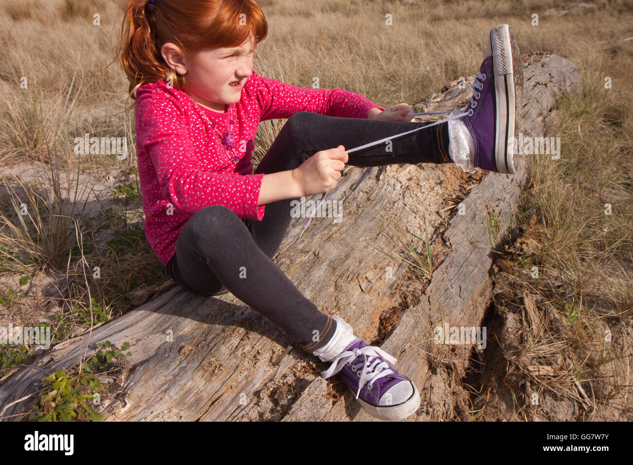 little red-haired girl tying up her shoelaces on purple sneakers Stock  Photo - Alamy