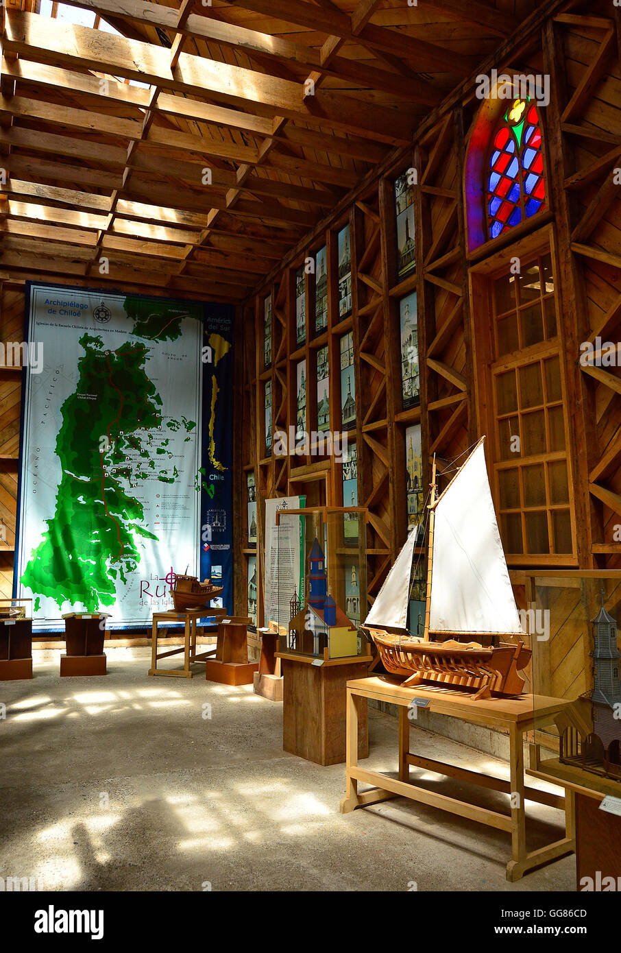 Exhibit at the Museo de las Iglesias de Chiloe, showing a model wooden sailing boat, a map of Chiloe Island, and stained glass. Stock Photo