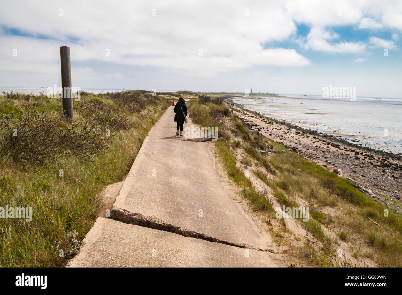 lady walking accross path with coastal errosion Stock Photo