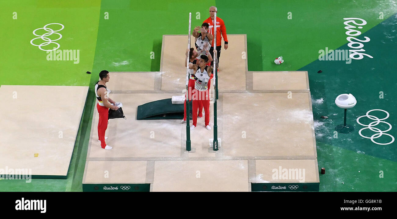 Rio de Janeiro, Brazil. 3rd Aug, 2016. Lukas Dauser (back-to-front), Andreas Bretschneider and Marcel Nguyen of Germany powder the parallel bars during a training session of the men's Artistic Gymnastics on pommel horse at Olympic Arena in Barra prior to the Rio 2016 Olympic Games in Rio de Janeiro, Brazil, 3 August 2016. Coach Andreas Hirsch (behind) and team-mate Andreas Toba watch this. Rio 2016 Olympic Games take place from 05 to 21 August. Photo: Bernd Thissen/dpa/Alamy Live News Stock Photo