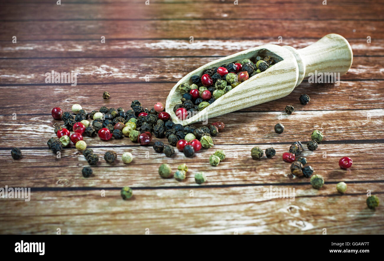 Mixed dried peppercorns on a wooden spoon. Stock Photo