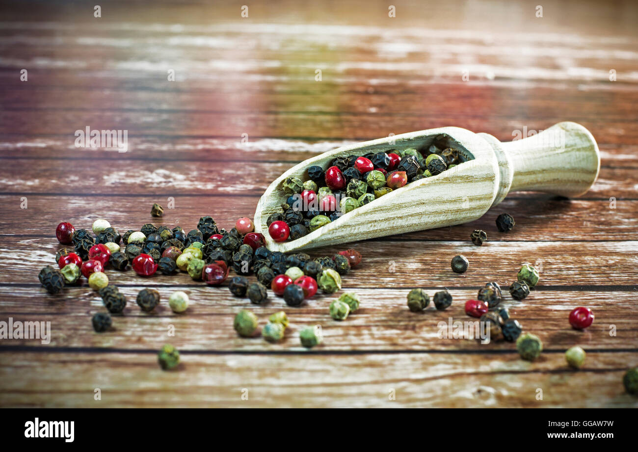 Mixed dried peppercorns on a wooden spoon. Stock Photo