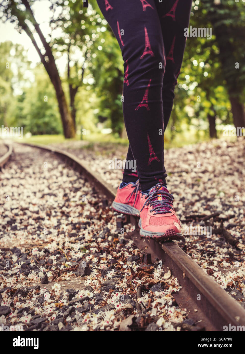 A girl in sneakers, balancing on rail. Stock Photo