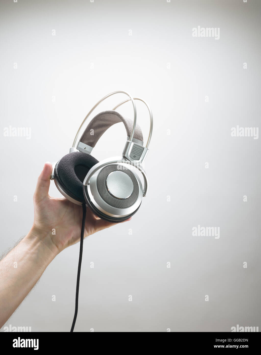 Male hand holding a pair of silver headphones Stock Photo Alamy