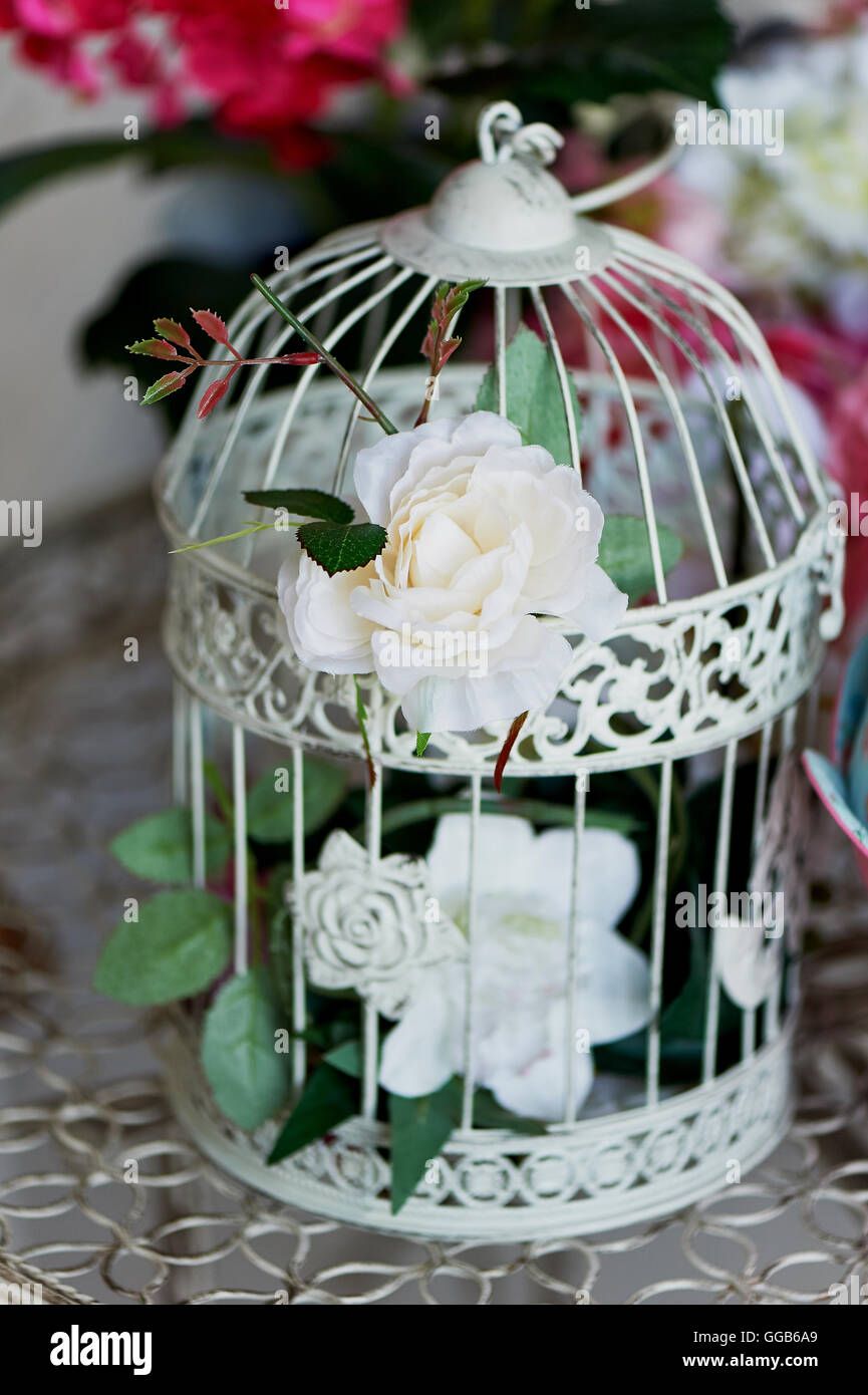 Vintage bird cage decorated with wreath made flowers, tiny roses