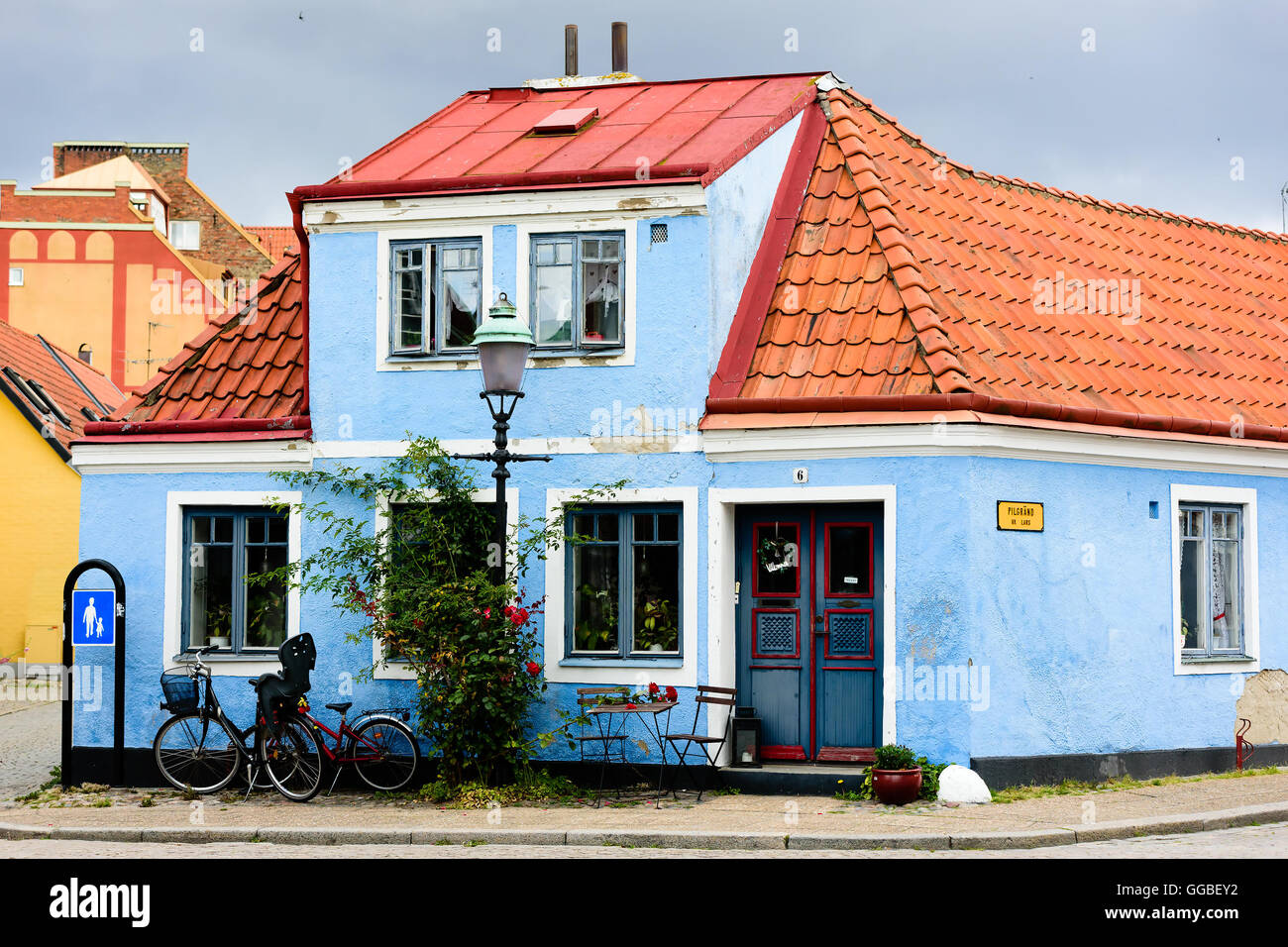 Ystad, Sweden - August 1, 2016: Old blue house in the corner of a street (Pilgrand) in the city. Small table and chairs under wi Stock Photo