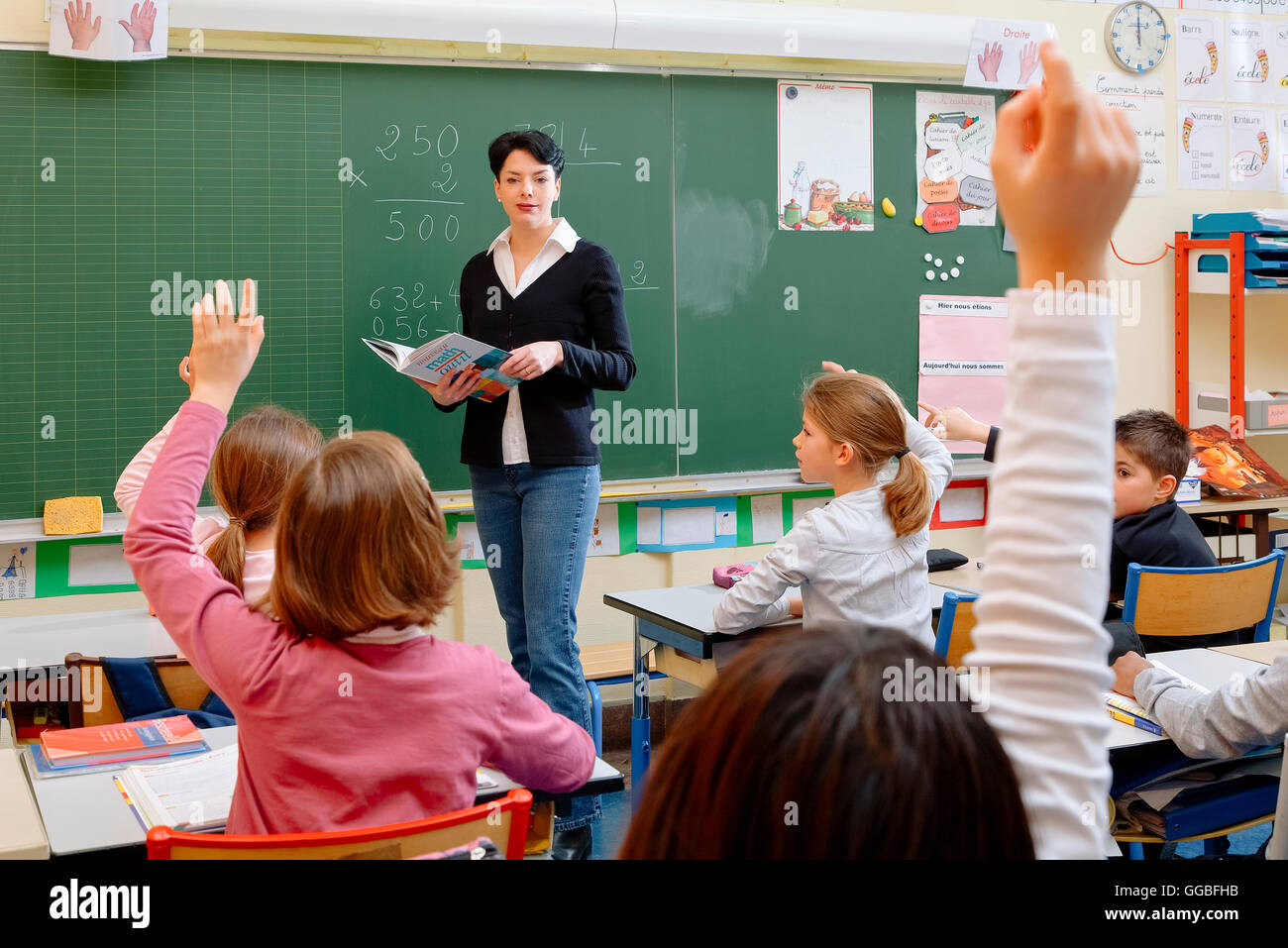 Portrait of diligent schoolkids and their teacher talking at lesson Stock Photo