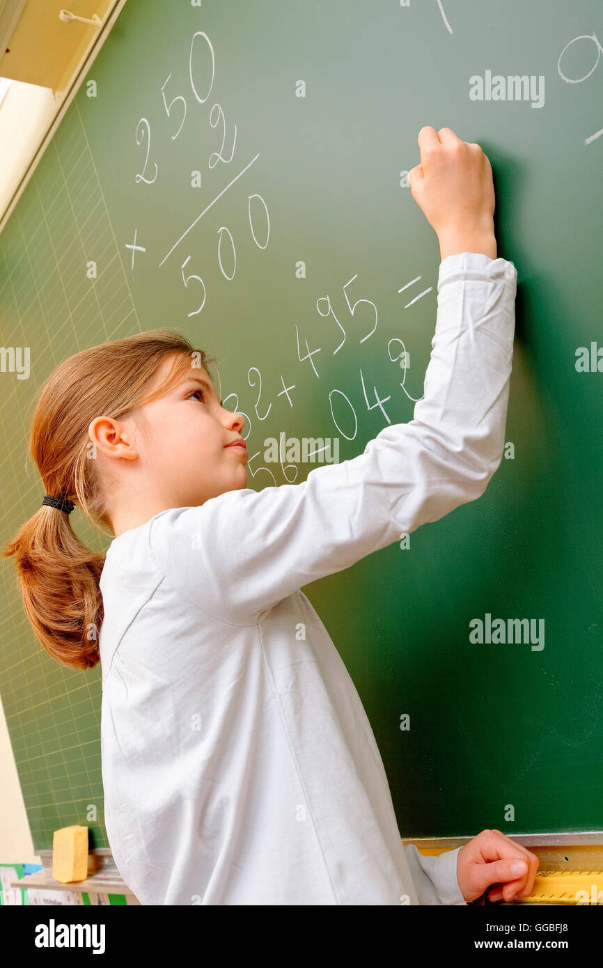 School girl writing on blackboard Stock Photo