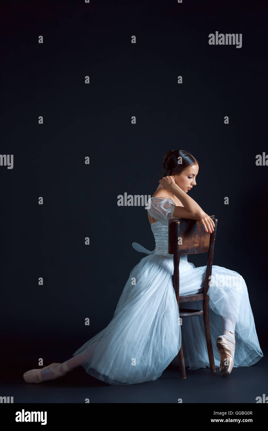 Portrait of the classical ballerina in white dress on black background