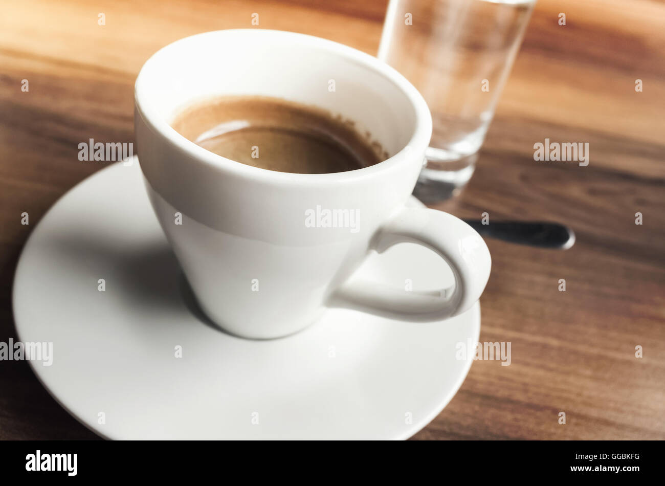 Cup of espresso coffee and small glass of fresh water stand on wooden table Stock Photo