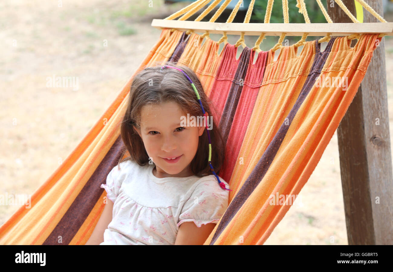 beautiful little girl with brown hair resting on a hammock in the summer Stock Photo