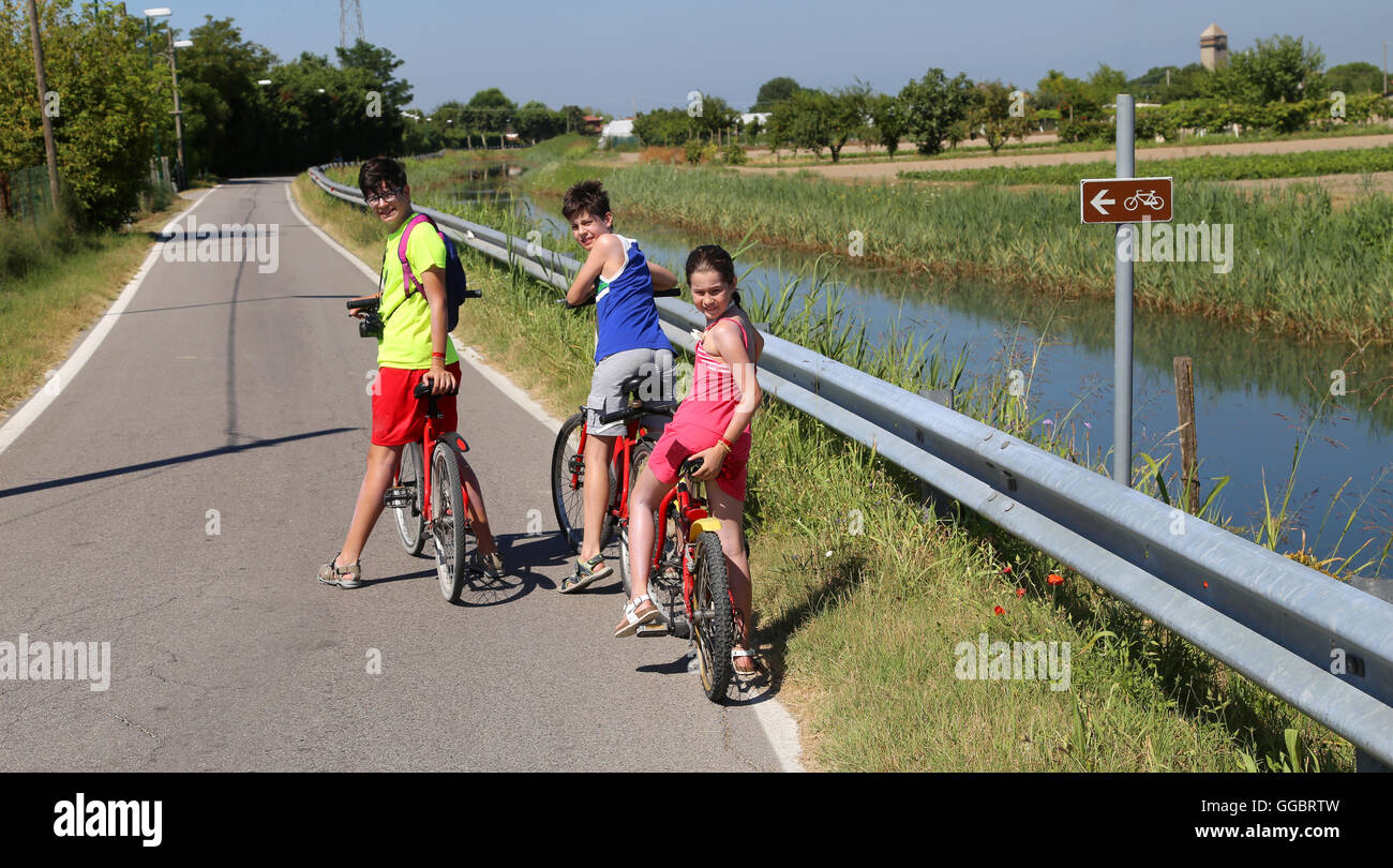 three young brothers by bike on the bike path during a trip in the summer Stock Photo