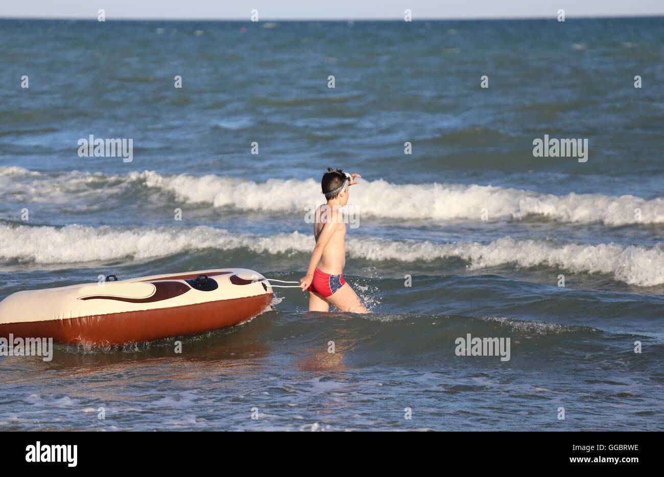 brave boy with the dinghy on choppy sea in summer Stock Photo