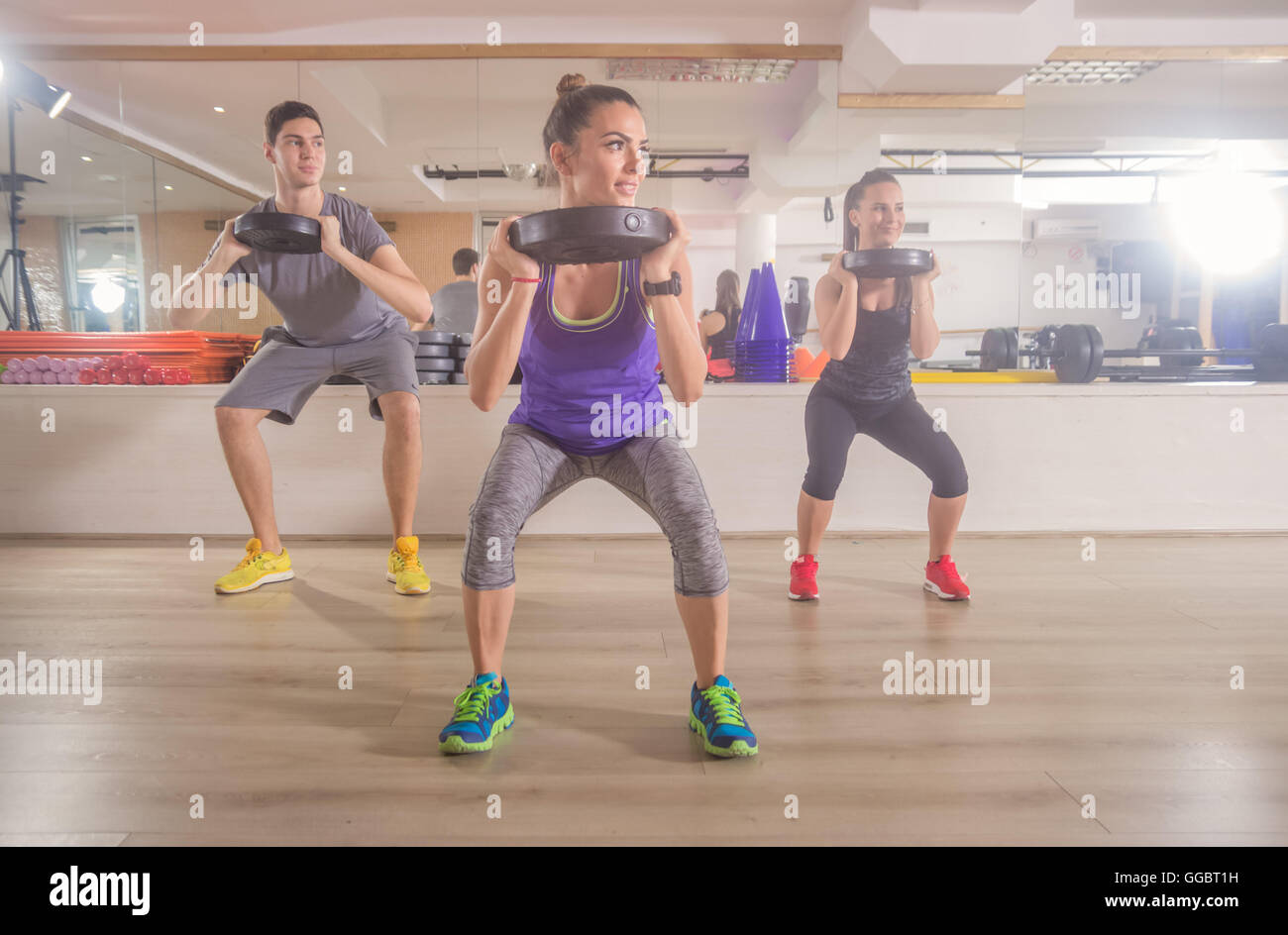 Three people fitness gym squat weights hand Stock Photo