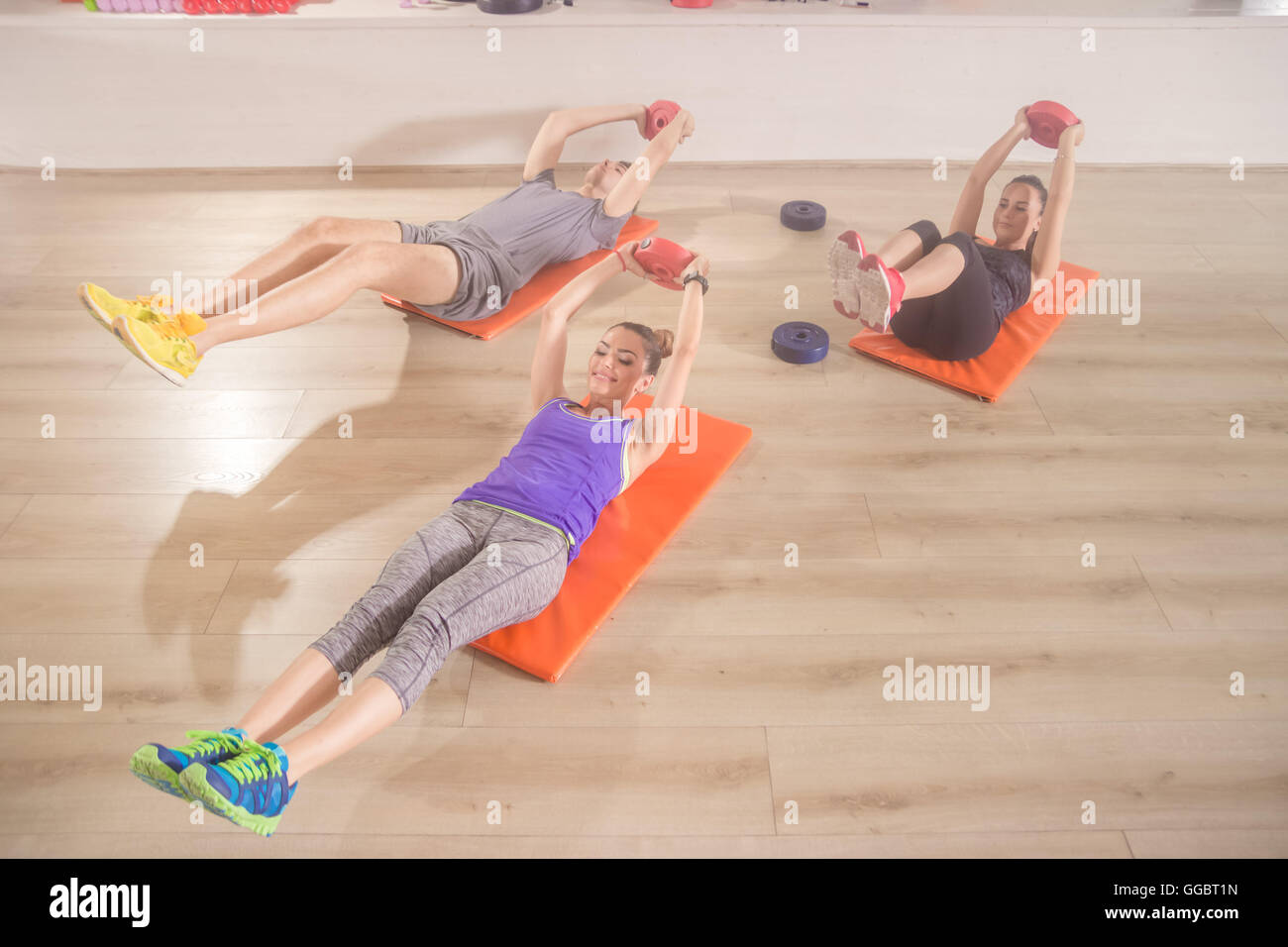 Three people fitness mat happy abs core exercise straight arm weights Stock Photo