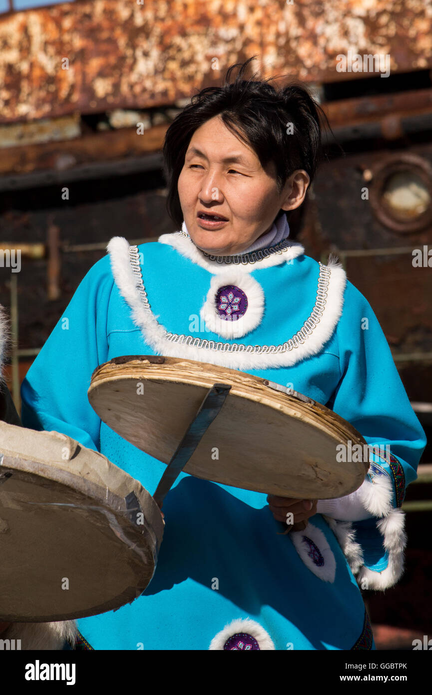 Russia, Komsomolskaya Bay, Chukotka Autonomous Okrug. Port of Provideniya. Native woman in traditional attire, drumming. Stock Photo