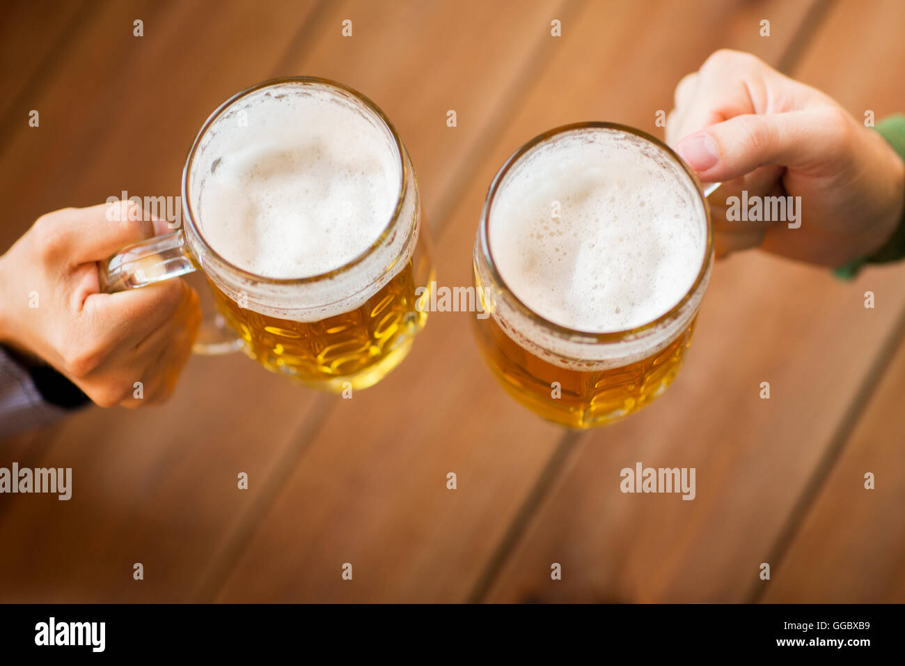 close up of hands with beer mugs at bar or pub Stock Photo