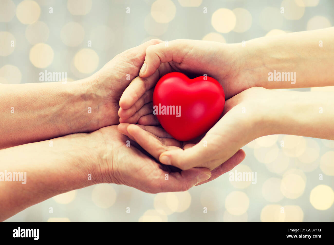 senior and young woman hands holding red heart Stock Photo - Alamy
