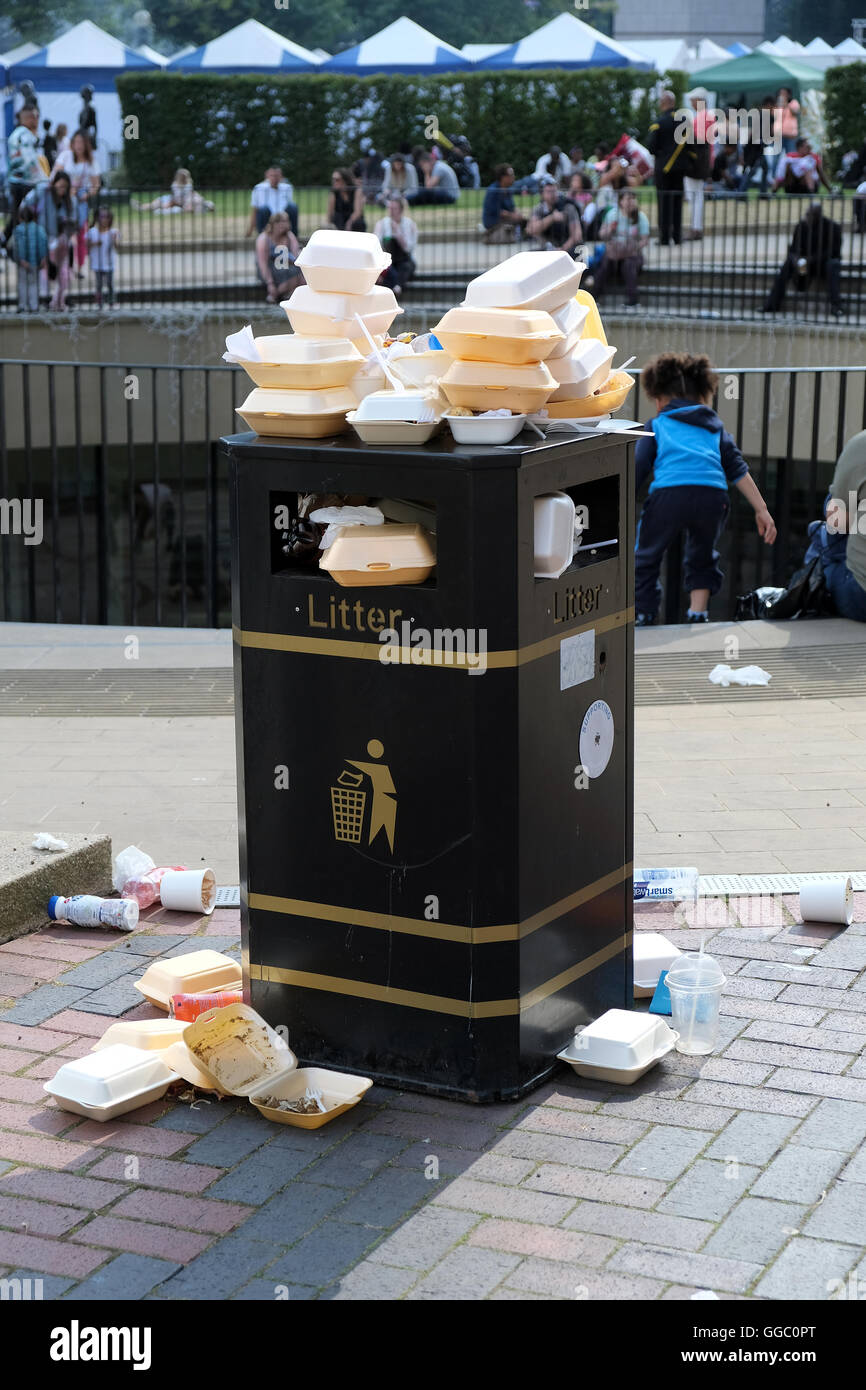 A street side public rubbish bin full to capacity and overflowing with fast food containers Stock Photo