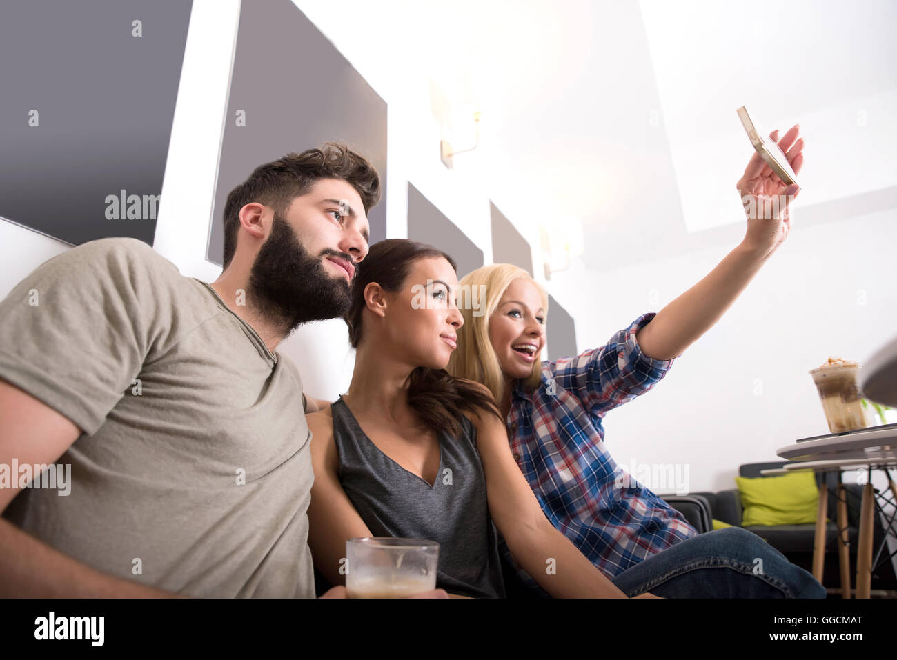 Friends siting at a table and taking a selfie in a coffee shop Stock ...