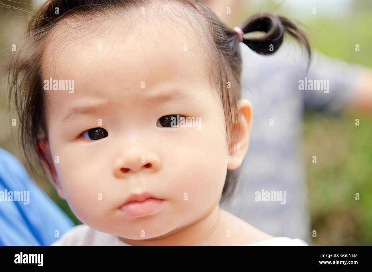 Sweet little girl outdoors with questionable eyes looking to the lens Stock Photo