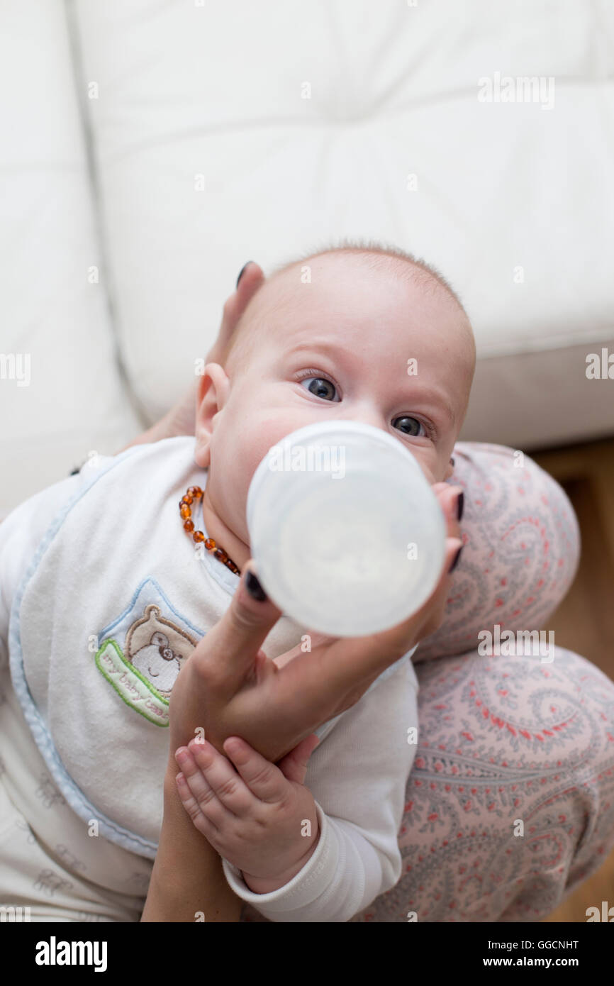 Mother gives baby drinking milk from a bottle Stock Photo