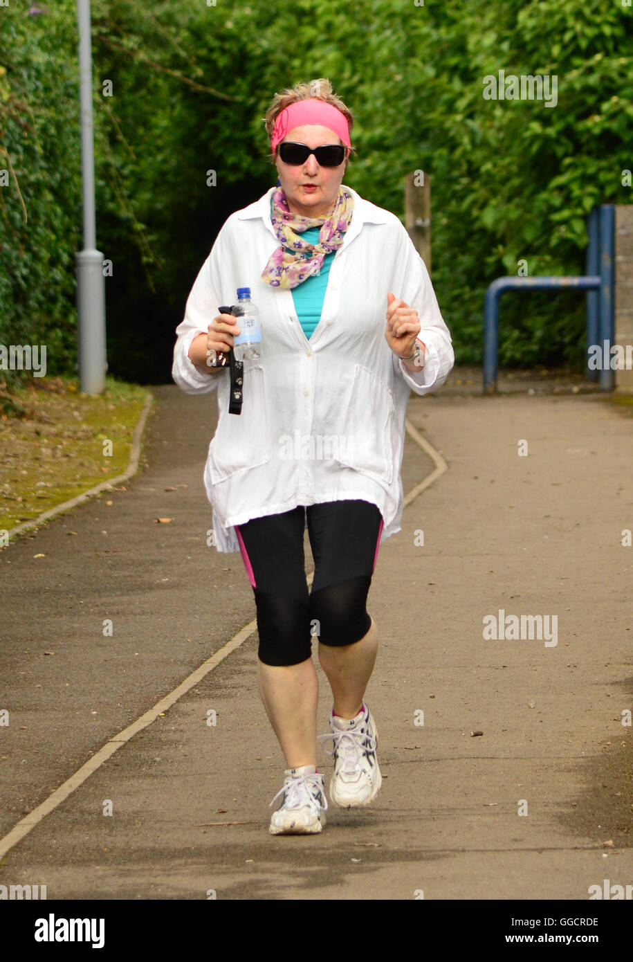 Woman in her 60s, wearing appropriate sporting gear, jogging Stock Photo