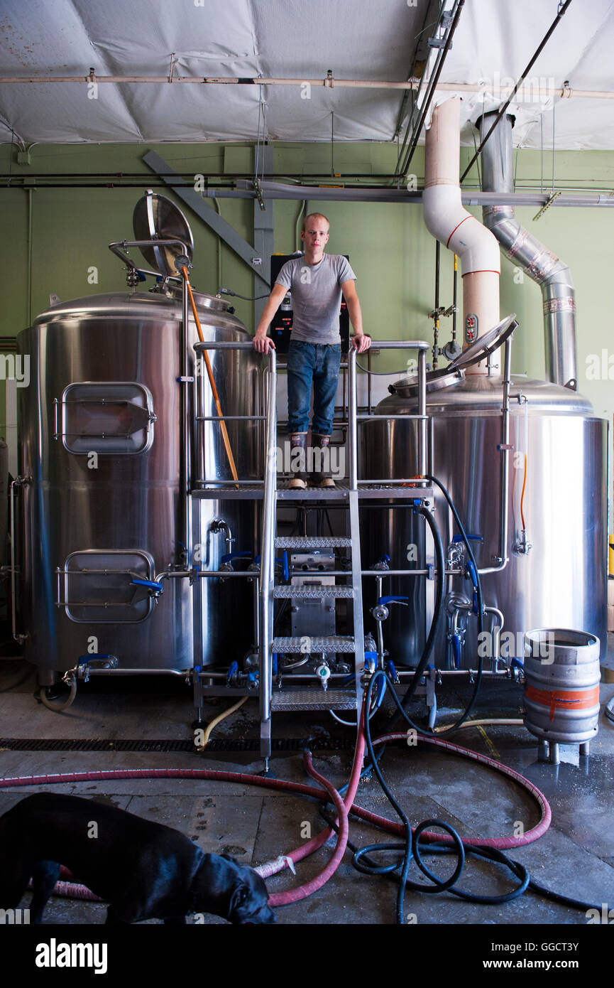 Brewer standing with fermentation tanks inside of Two Beers Brewery in