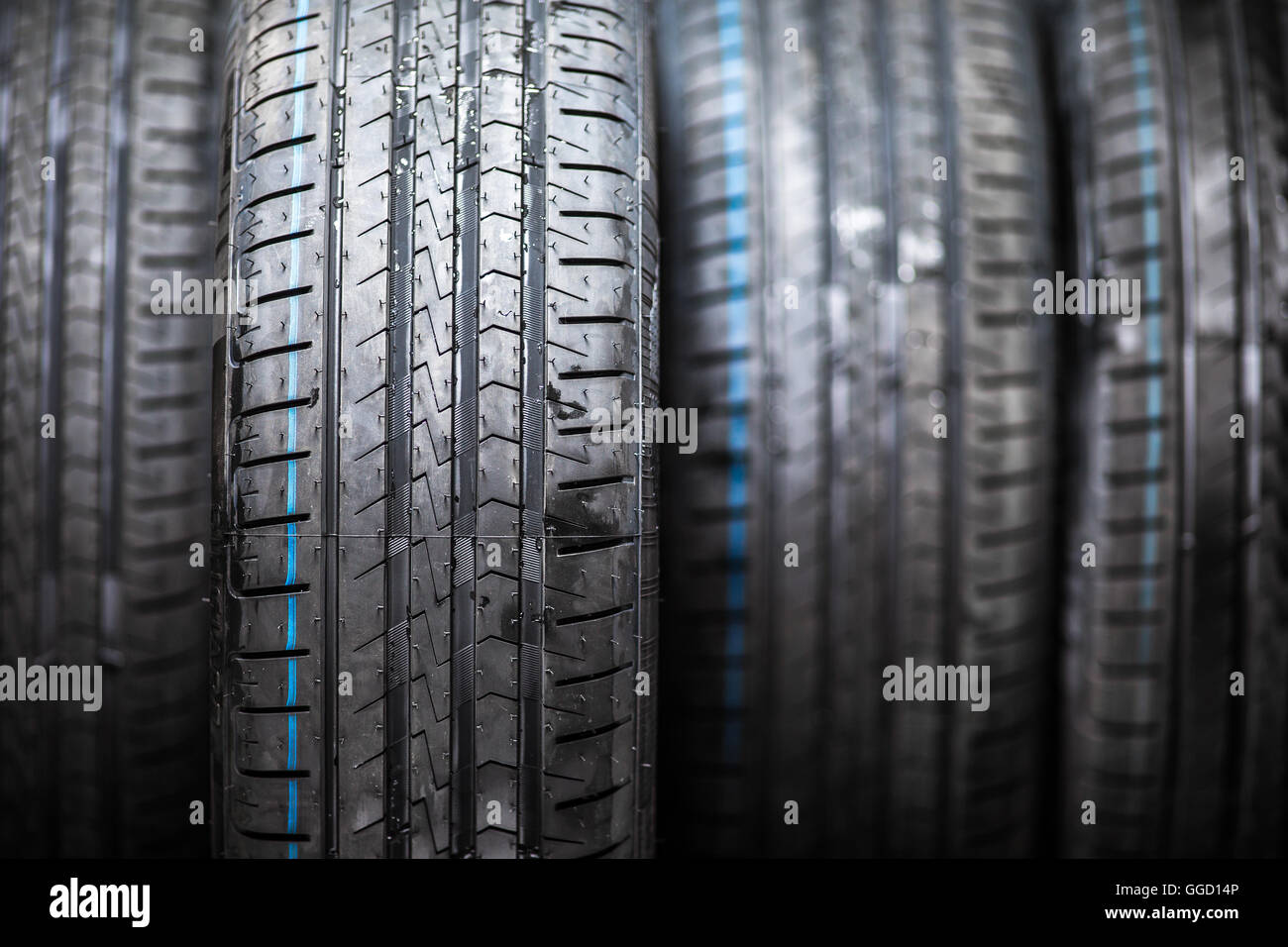 Stack of brand new high performance car tires on clean lowkey black