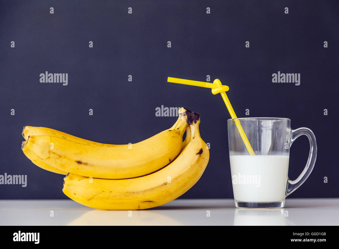 Bunch of bananas and milk. Tube cocktail. Dark background Stock Photo