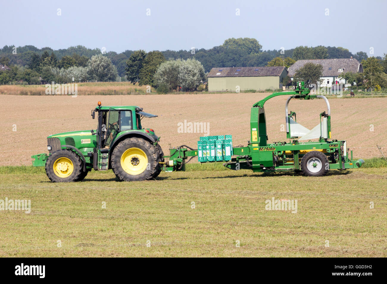 Tractor wrapping a bale of hay in plastic protection Stock Photo