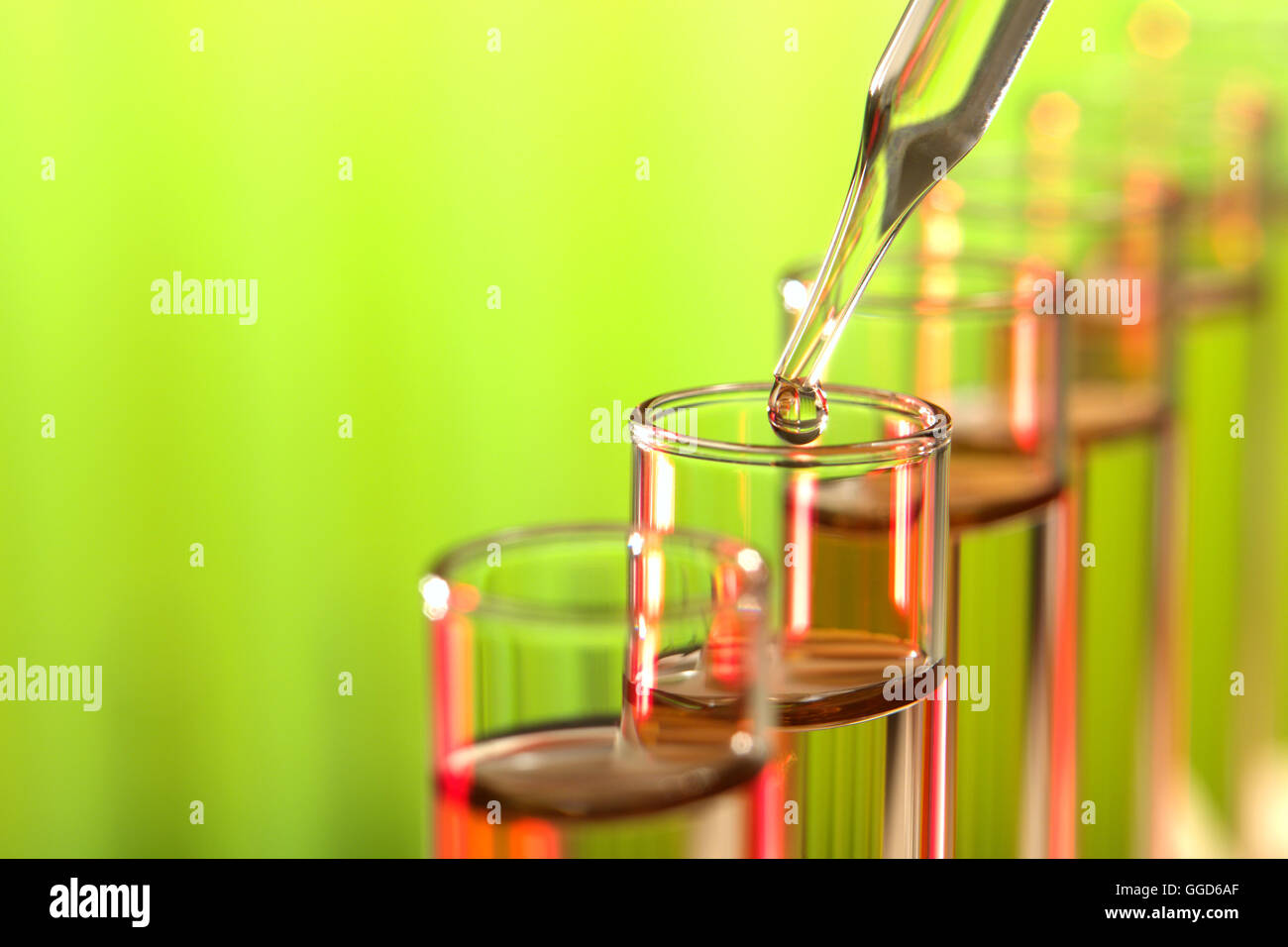 Laboratory glass pipette with drop of liquid over test tubes for a ...