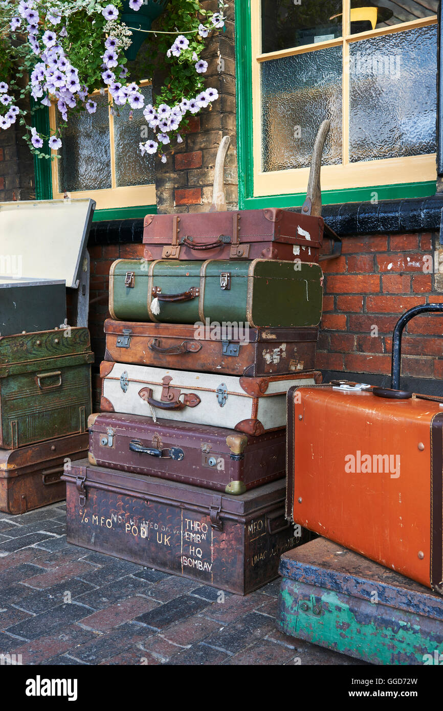 Old suitcases at a steam railway station stacked on a barrow cart, on the platform Stock Photo
