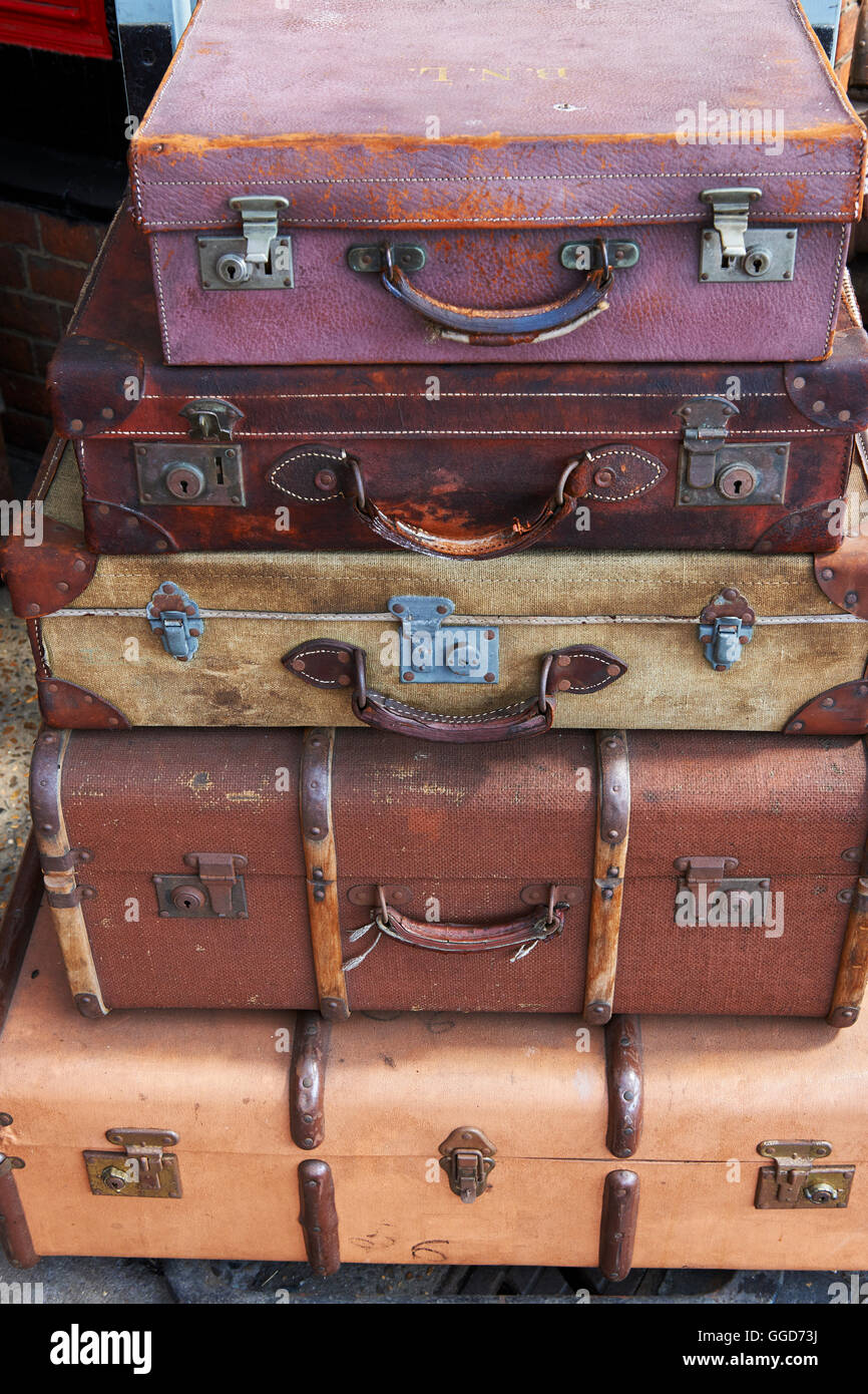 Old suitcases at a steam railway station stacked on a barrow cart, on the platform Stock Photo
