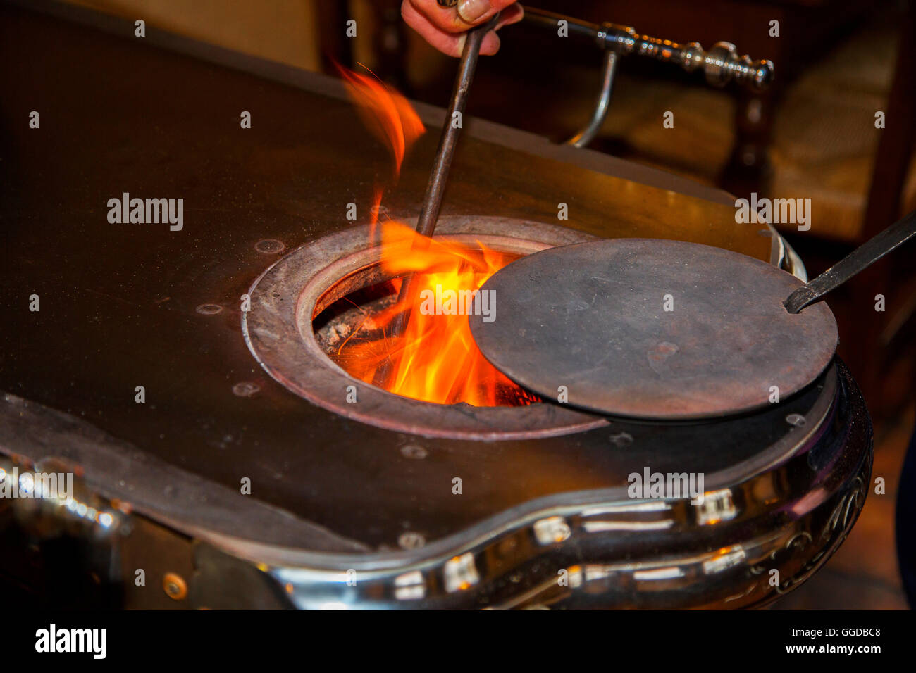 Vintage cast-iron coal stove / Leuvense stoof showing flames and poker Stock Photo