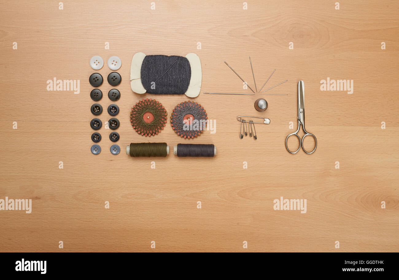 Sewing kit. Scissors, bobbins with thread and needles on wooden table ...