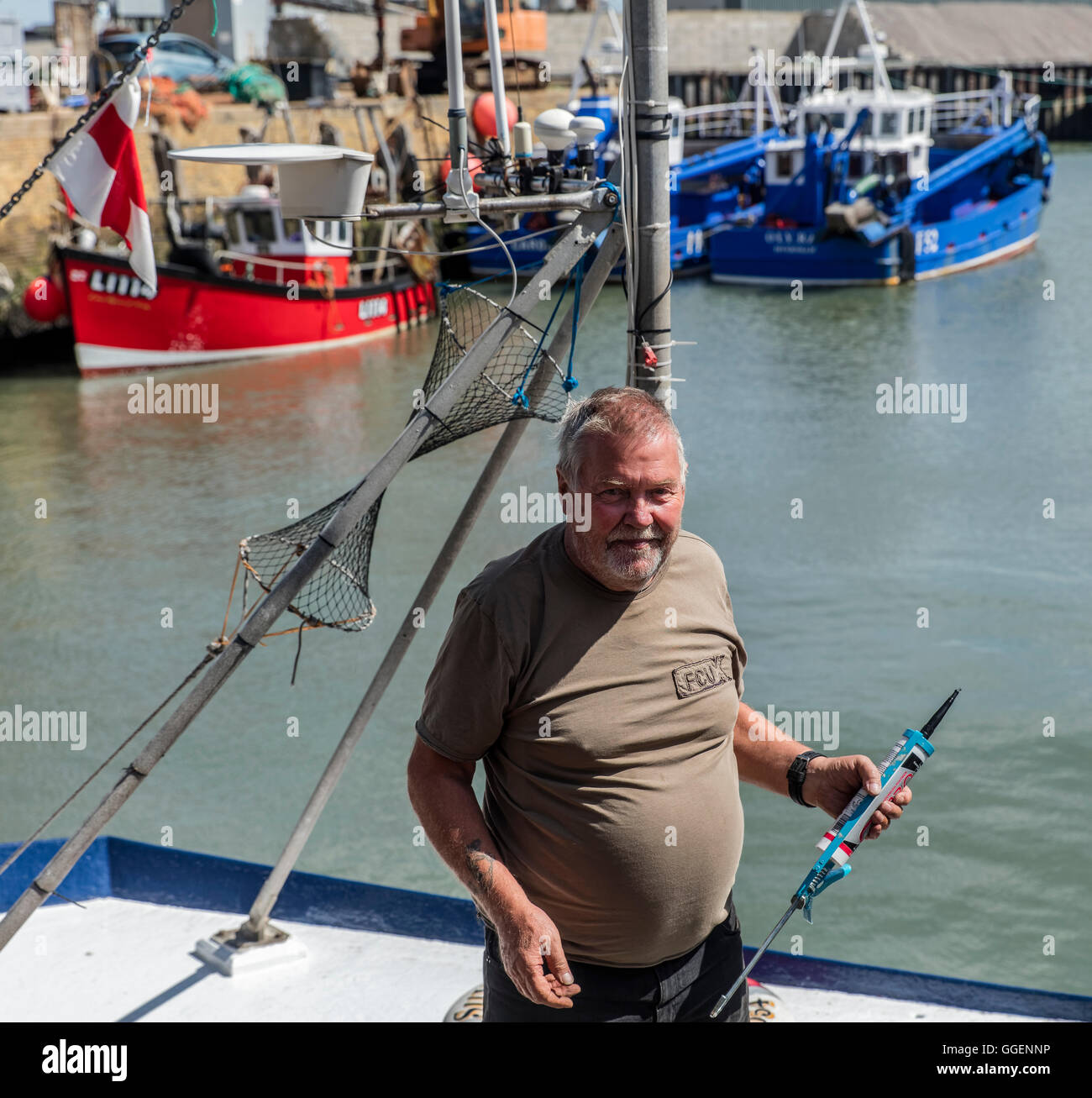 Fisherman repairing his fishing boat at Whitstable harbour in Kent Stock Photo