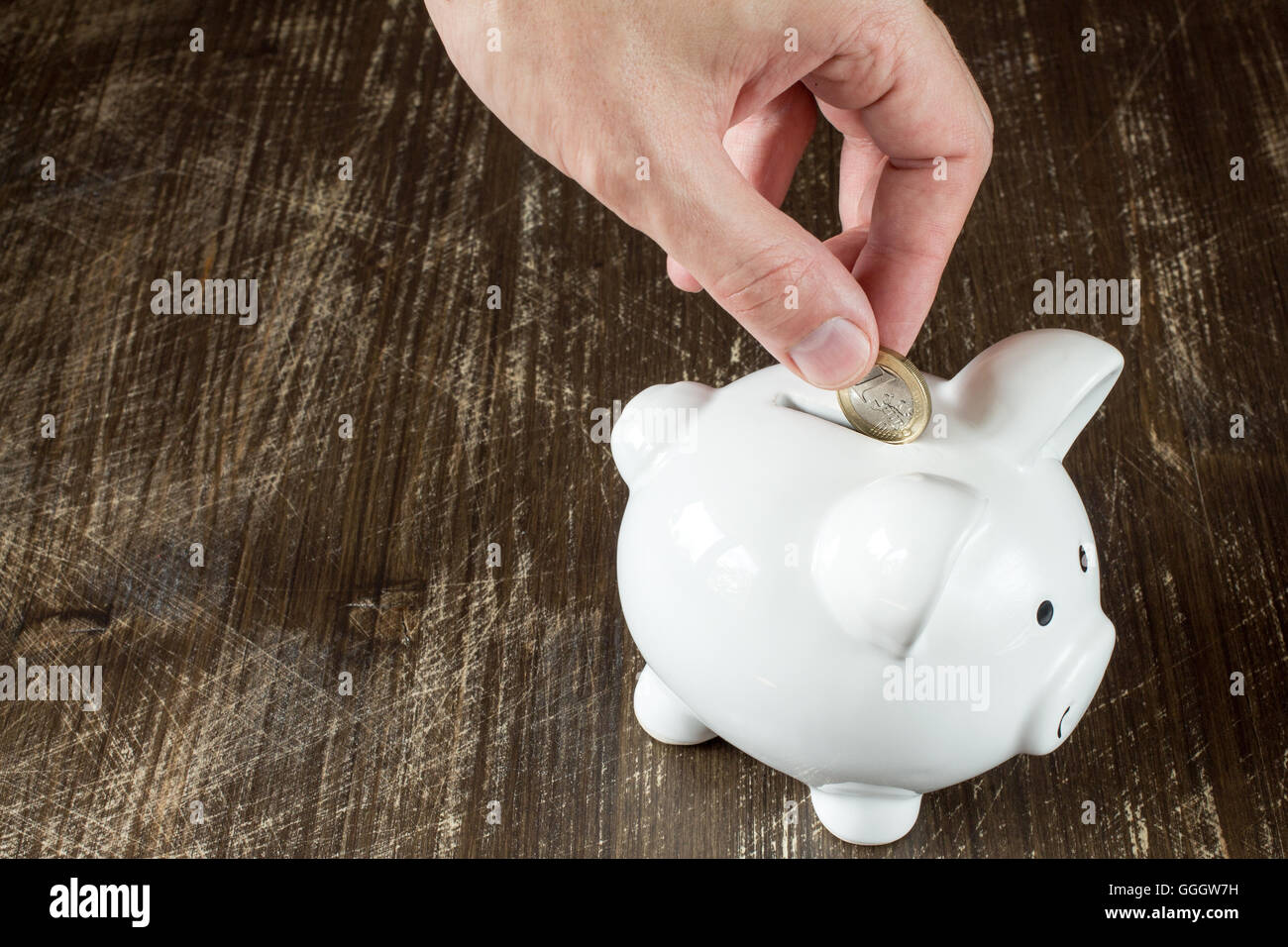 Man putting Euro coin in piggy bank Stock Photo - Alamy