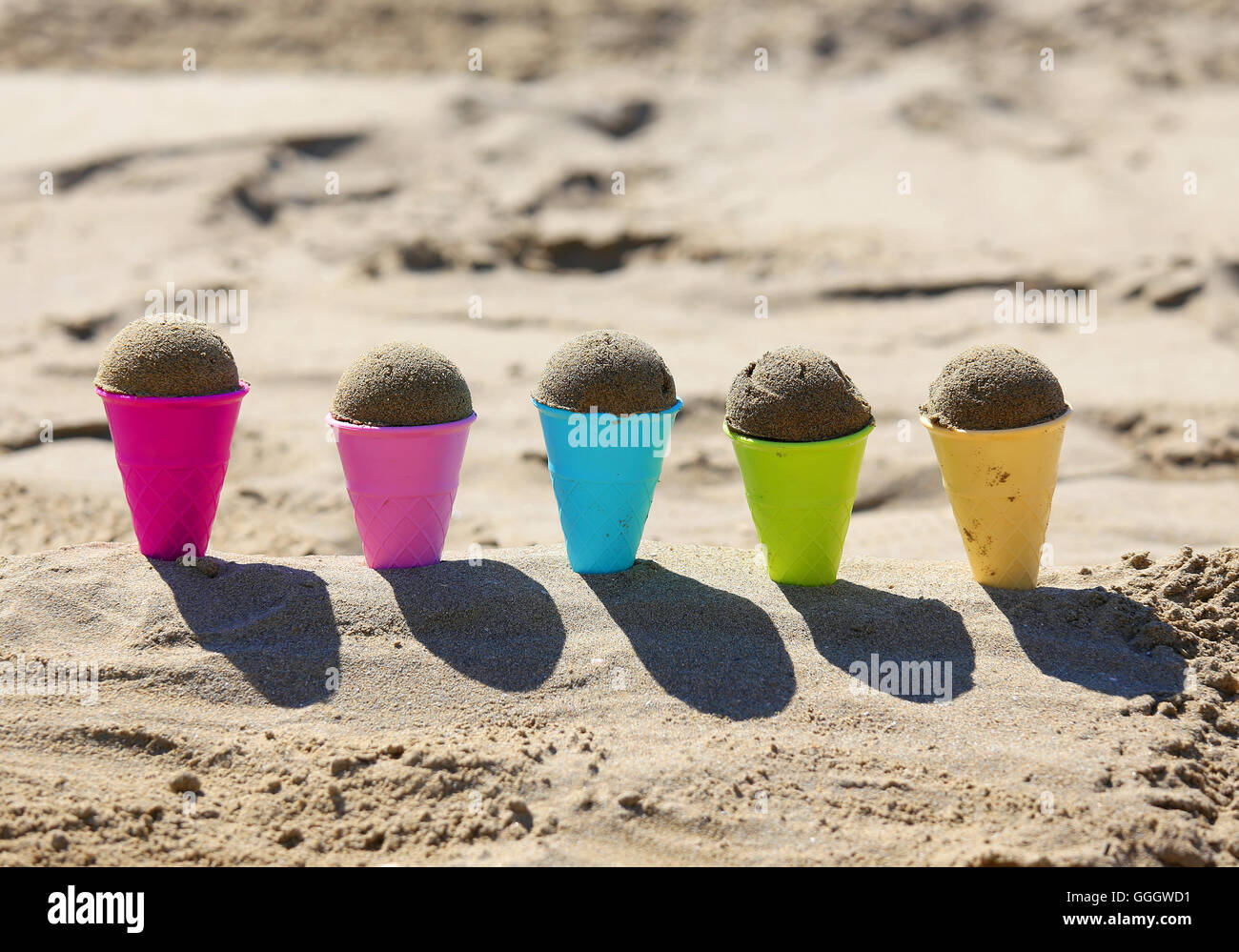 five big toy ice cream cones on the beach with sand in summer Stock