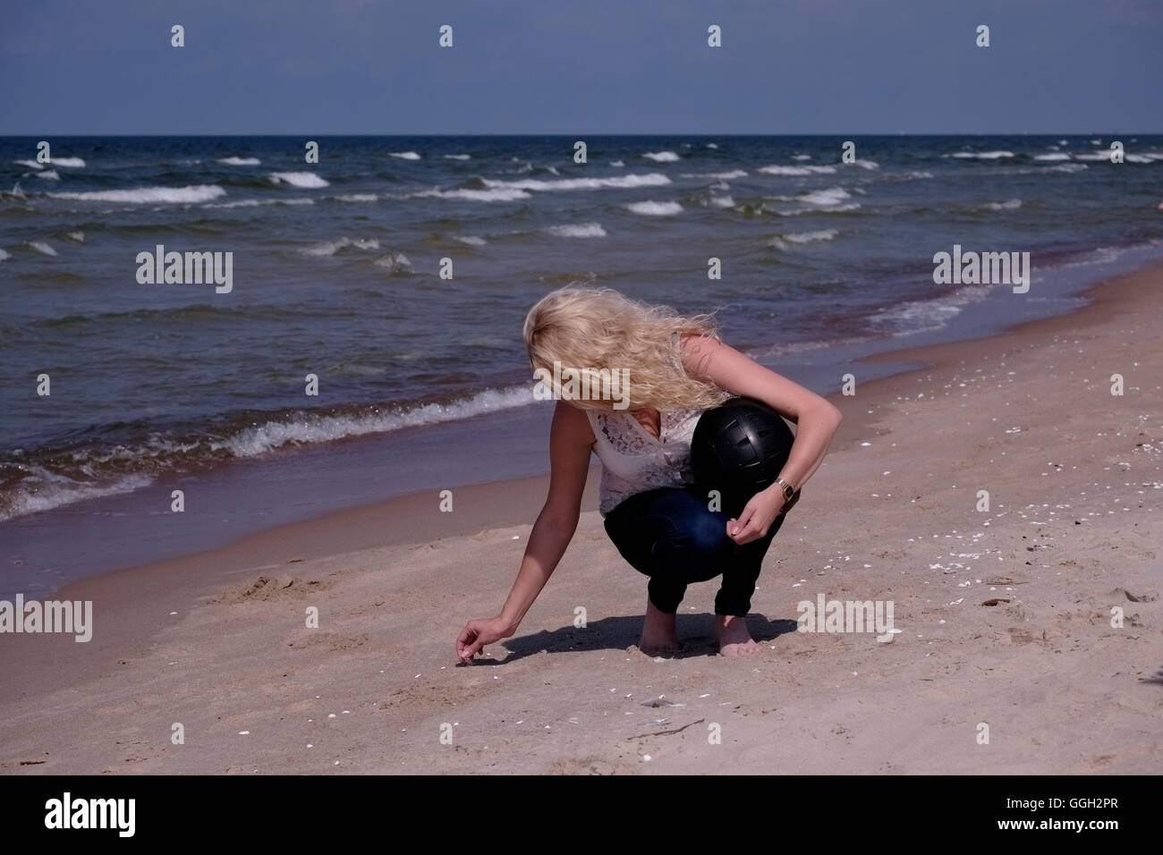 Young Lithuanian woman collecting seashells at the northern seacoast of ...