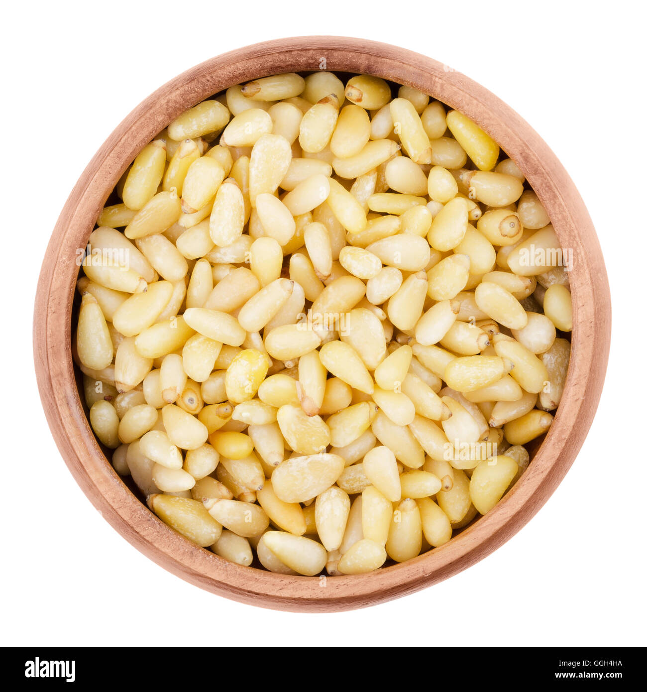 Shelled pine nuts in a bowl on white background. Edible seeds of Korean pines family Pinaceae, genus Pinus, in a wooden bowl. Stock Photo