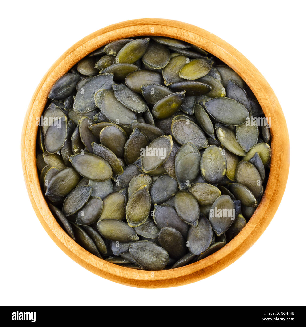 Pepita pumpkin seeds in a bowl on white background. Flat green edible summer squash seeds. Stock Photo